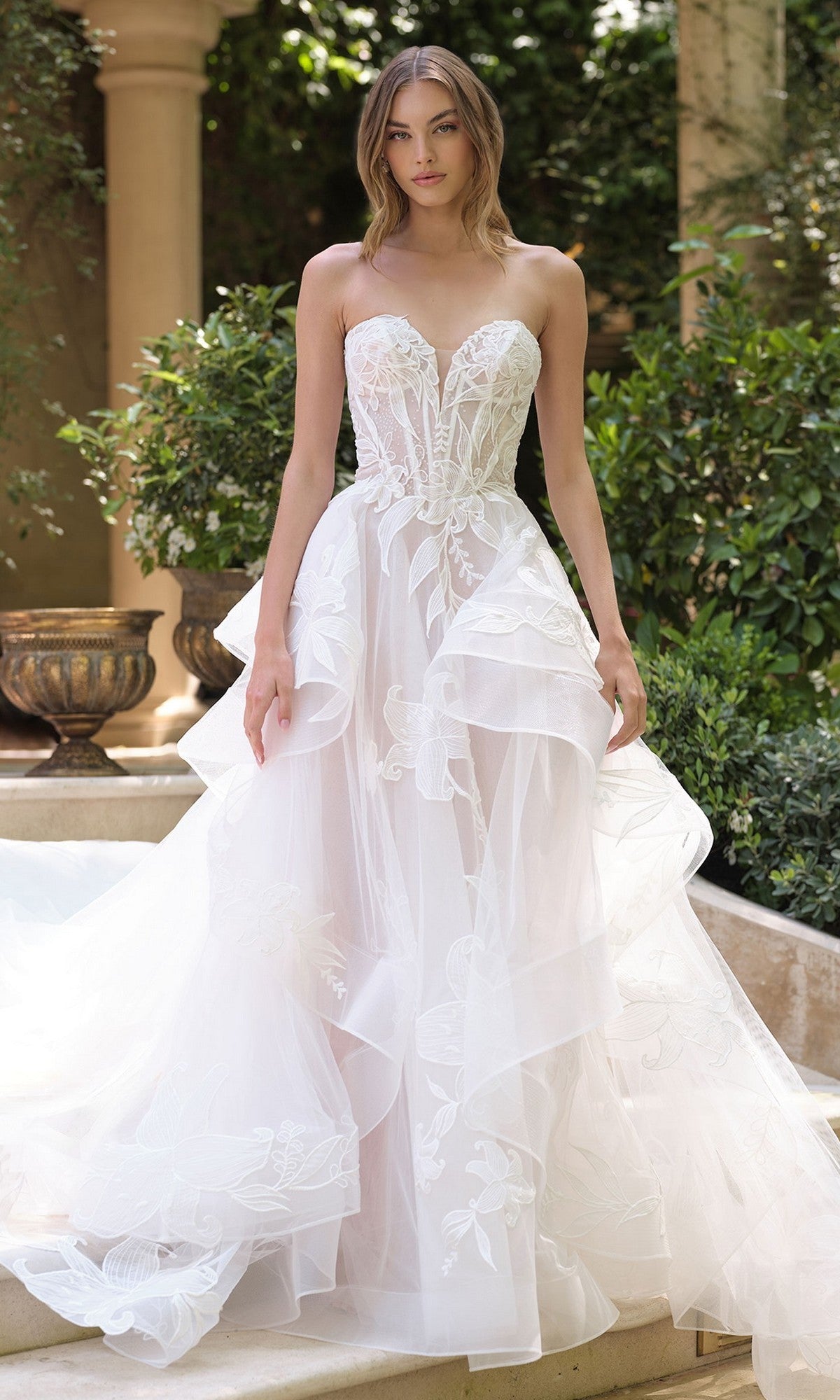 A woman stands outdoors in the Andrea and Leo WL059 long wedding dress, featuring off white/nude tones, sheer floral embroidery, and a layered tulle skirt for an ethereal bridal look.